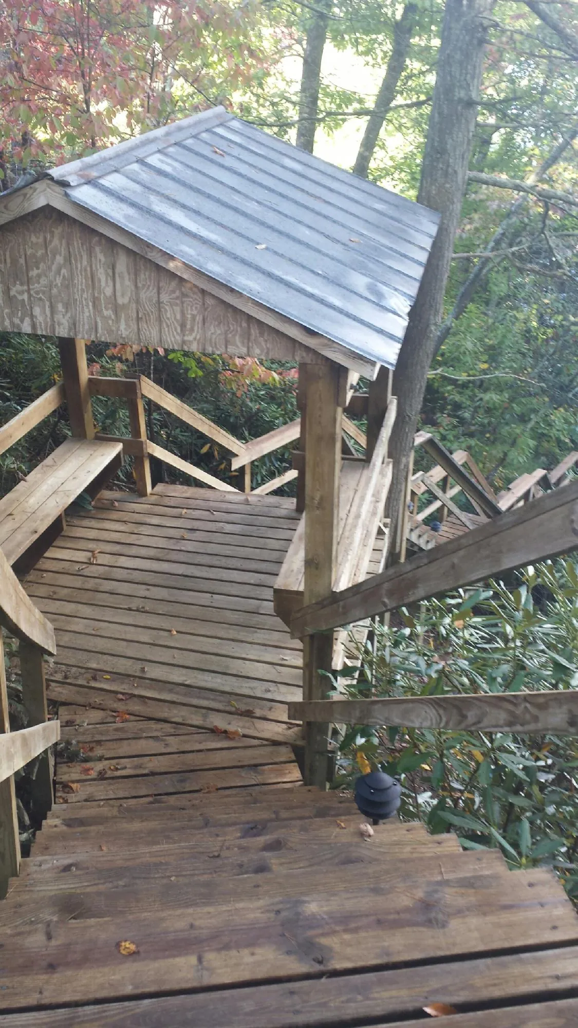 Metal roofed shelter over wooden steps on a wooded walkway — Skylight Repair & Installation work by our crew in Lincoln